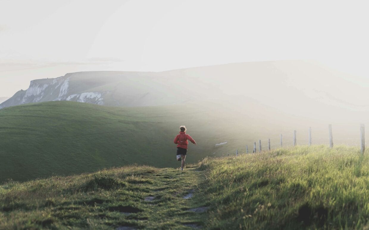 Corredor em sua primeira trilha de trail running em caminho de terra com vegetação ao redor