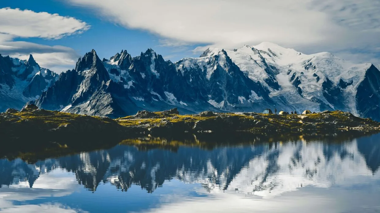6 Trilhas icônicas do mundo: os percursos que todo corredor de trail sonha em correr 10 Corredor em trilha icônica do mundo com paisagem de montanha e céu azul ao fundo