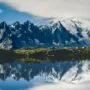 6 Trilhas icônicas do mundo: os percursos que todo corredor de trail sonha em correr 6 Corredor em trilha icônica do mundo com paisagem de montanha e céu azul ao fundo