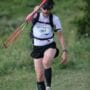 Corredor caminhando na subida de trail running em trilha íngreme com bastões nas mãos