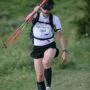 Corredor caminhando na subida de trail running em trilha íngreme com bastões nas mãos