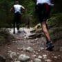 Corredor em trilha de terra com vegetação nativa ao fundo durante treino de trail running