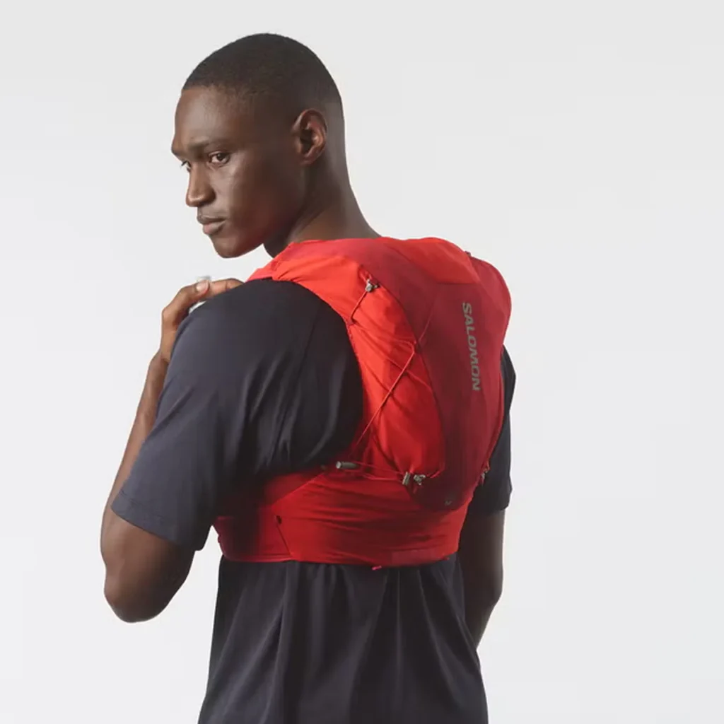 Corredor usando colete Salomon ADV Skin 12 em trilha de montanha durante prova de trail running