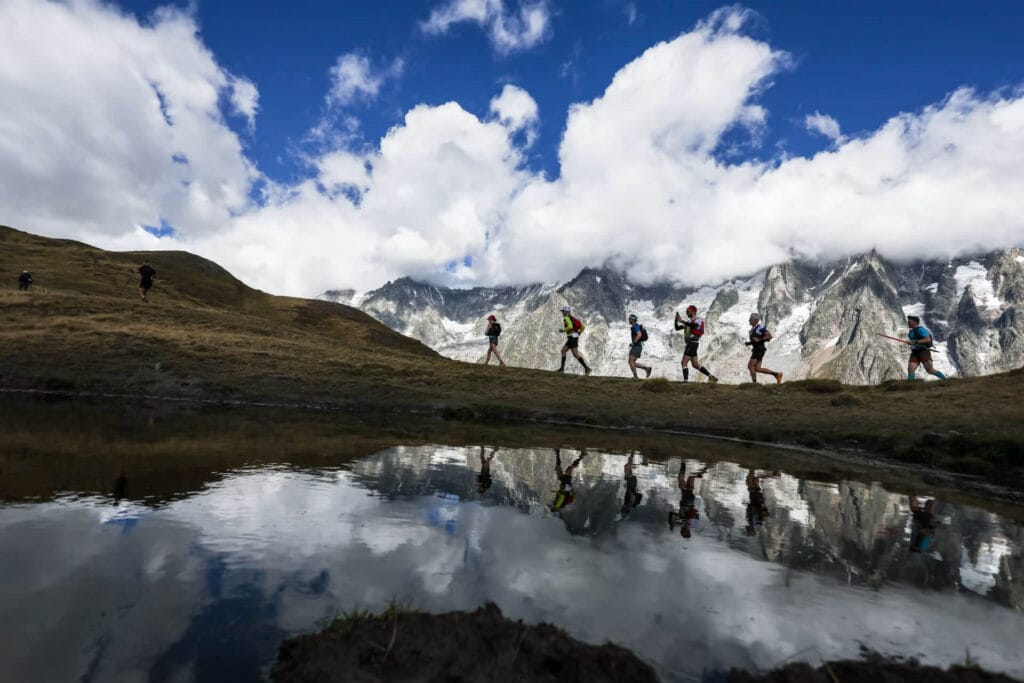 corredores em crista alpina com Mont Blanc nevado ao fundo no UTMB