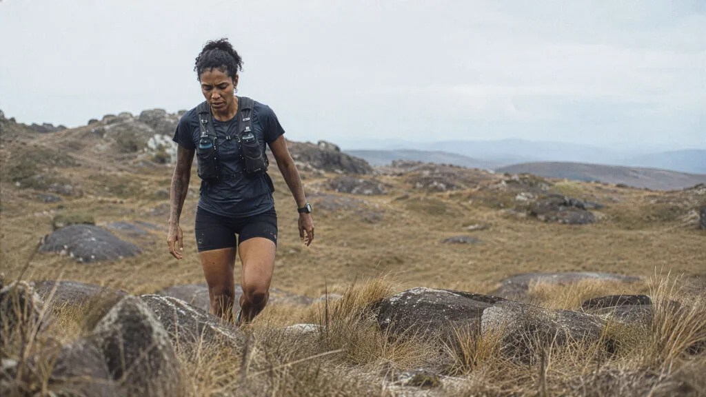 Preparação para ultramaratona: corredora em campos de altitude com fadiga visível após longão de treino