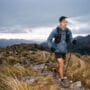 Equipamentos para ultra trail no inverno: corredor com anarok e bastões em campos de altitude ao amanhecer