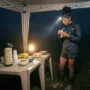 Nutrição para ultra trail de inverno em altitude: o que muda quando o frio e a hipóxia entram em cena 5 Nutrição ultra trail inverno: corredora se alimentando em posto de abastecimento noturno em campo de altitude