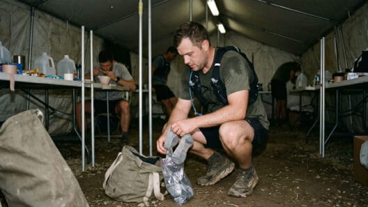 Drop bag ultra trail: corredor organizando bolsa de apoio dentro de aid station durante prova com saquinhos transparentes
