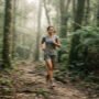 Corrida e saúde mental: corredora na trilha da Mata Atlântica com luz suave da manhã e passo tranquilo